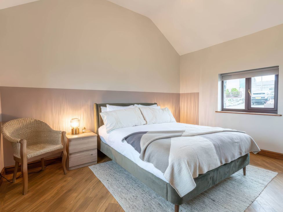 A bedroom with a bed and a chair at Wren Cottage in Llangaffo