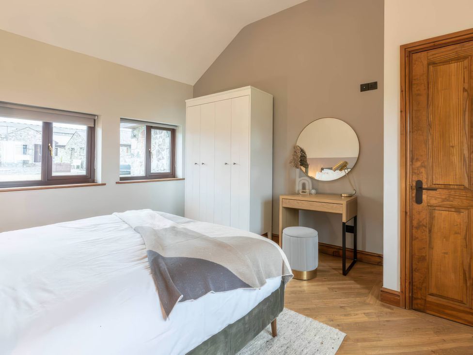 A bedroom with a bed, wardrobe, and mirror at Wren Cottage in Llangaffo
