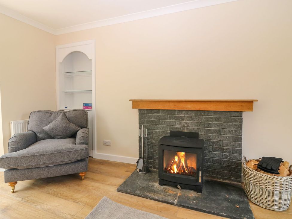 A living room with an armchair and a fireplace at Bankhead Of Lour Cottage in Forfar