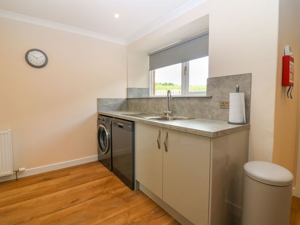 A kitchen with appliances including a washing machine and a dishwasher at Bankhead Of Lour Cottage Forfar