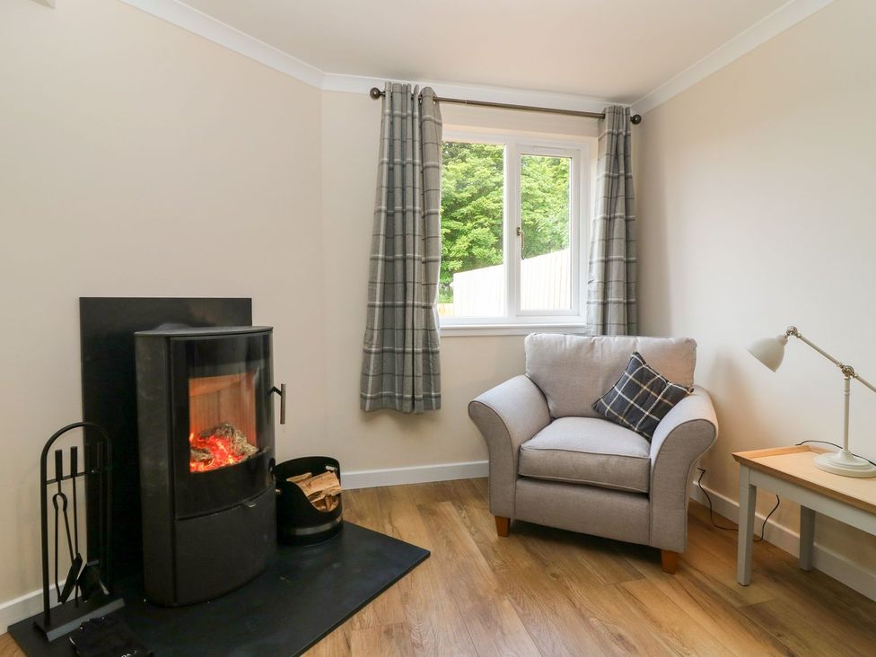 A living room with an armchair and fireplace at Bankhead Of Lour Cottage in Forfar