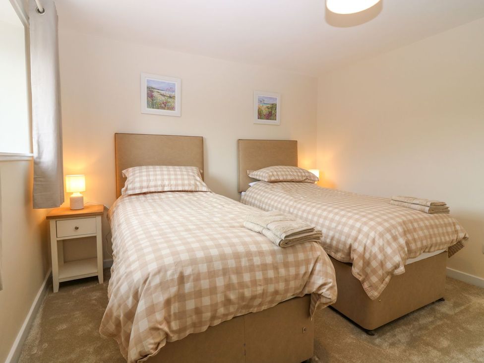 A bedroom with twin beds and bedside table at Bankhead Of Lour Cottage in Forfar