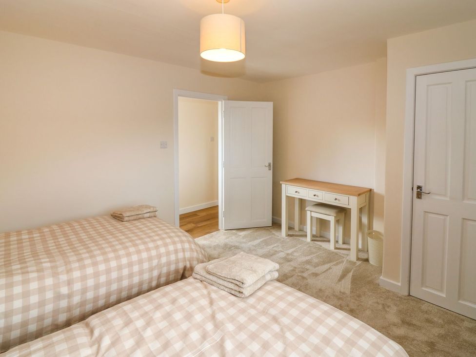 A bedroom with twin beds and a desk at Bankhead Of Lour Cottage in Forfar
