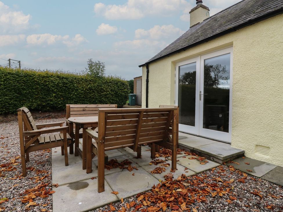 An outdoor patio with a table and chairs at Bankhead Of Lour Cottage Forfar