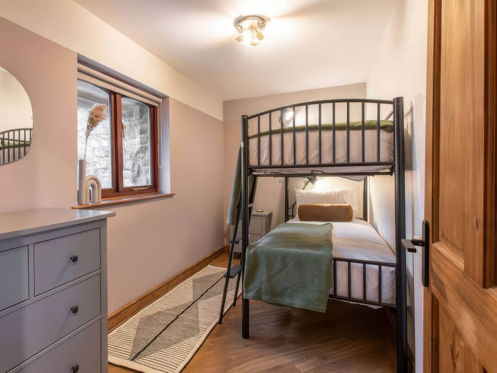 A bedroom with a bunk bed and dresser at Blue Bird Cottage in Llangaffo