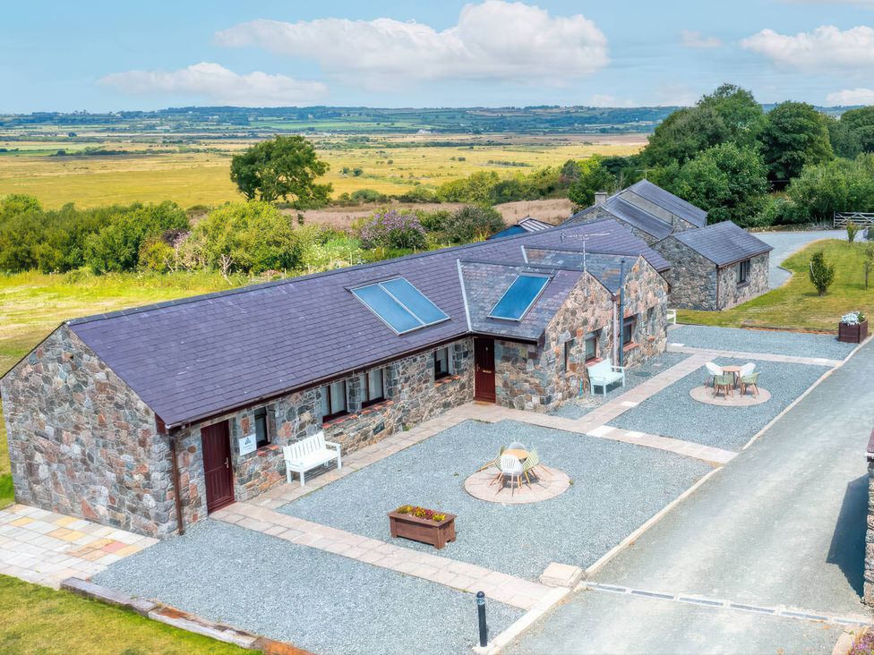 A stone cottage with outdoor seating areas at Blue Bird Cottage in Llangaffo