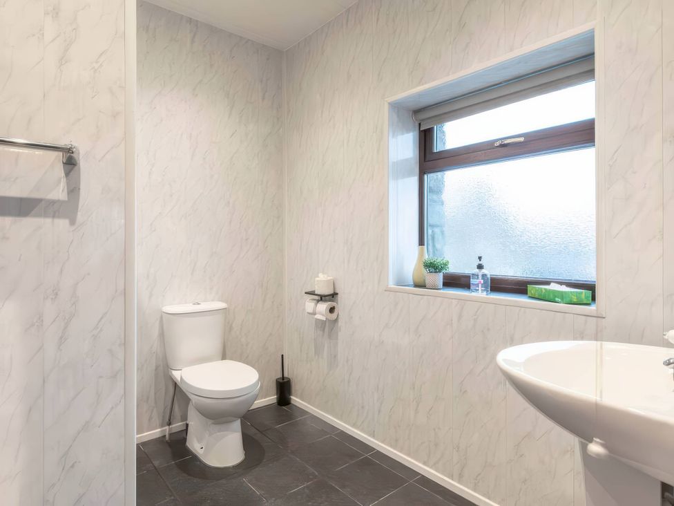 A bathroom with a toilet and sink at Blue Bird Cottage in Llangaffo