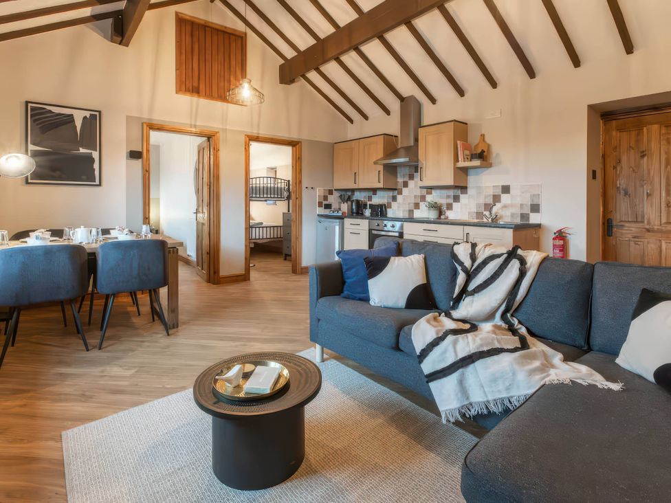 A living room with a sofa and dining table at Blue Bird Cottage in Llangaffo
