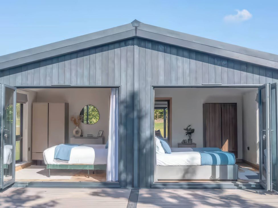 Two bedrooms with beds and wardrobes at Isca Lodge - With Decking - Lodge 1, Wombleton