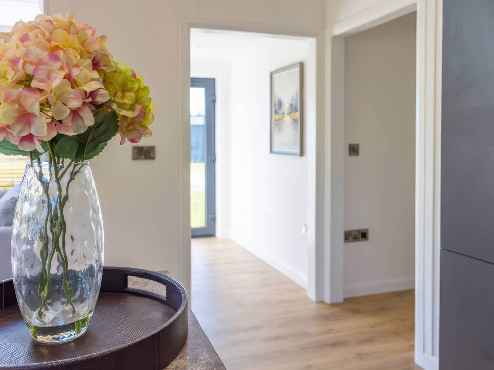 A hallway with a flower arrangement in a vase at Isca Lodge - With Decking - Lodge 1, Wombleton