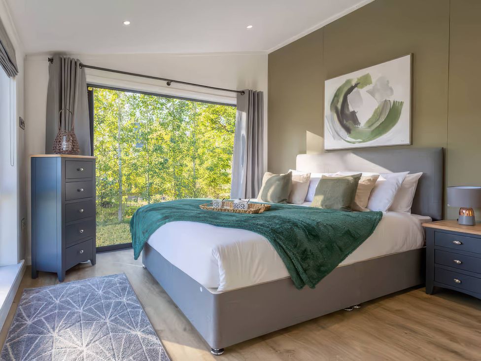 A bedroom with a bed and nightstand at Isca Lodge - With Decking - Lodge 1, Wombleton
