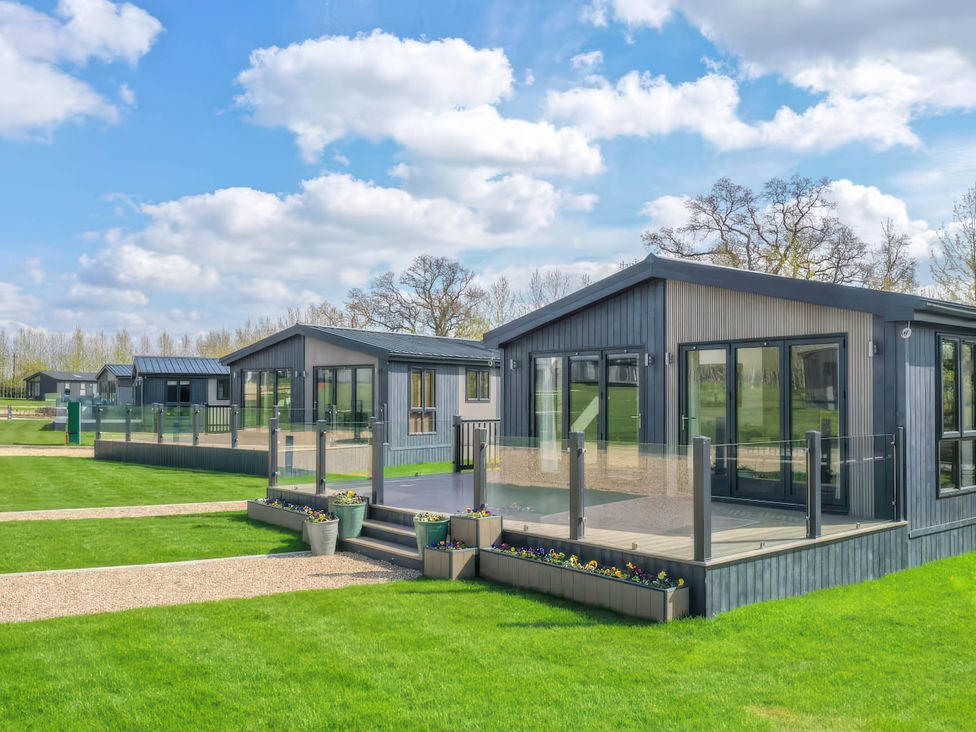 A view of multiple lodges with glass railings and planters at Isca Lodge - With Decking - Lodge 1 in Wombleton