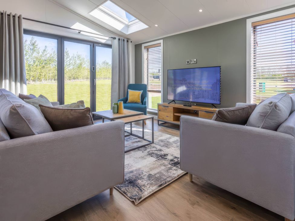 A living room with a sofa and television at Isca Lodge in Wombleton