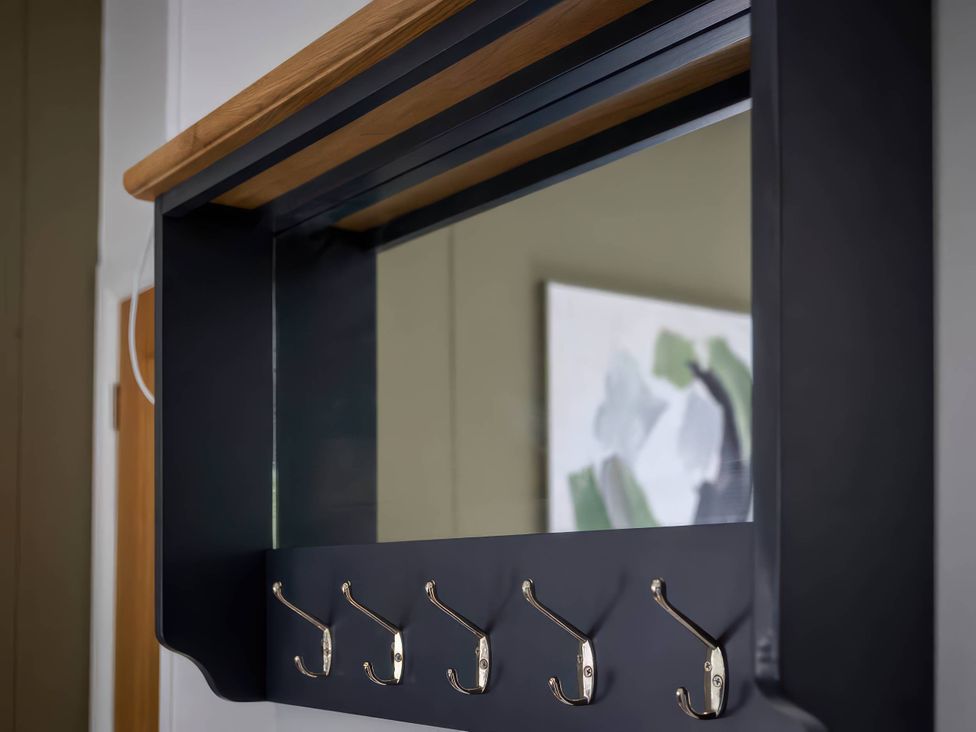 A mirror with coat hooks and a wood shelf at Isca Lodge in Wombleton