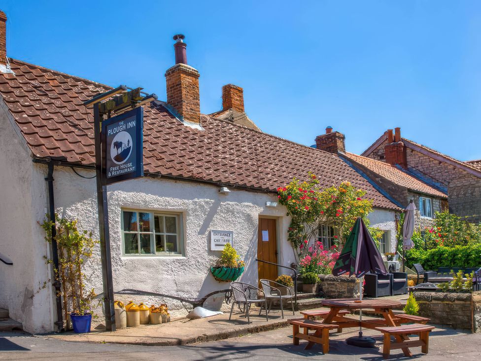 An outdoor seating area with tables and flowers at The Plough Inn in Wombleton