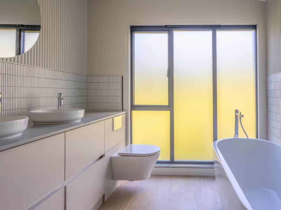 A bathroom with a bathtub, toilet, sink, and window at Rye Lodge in Wombleton