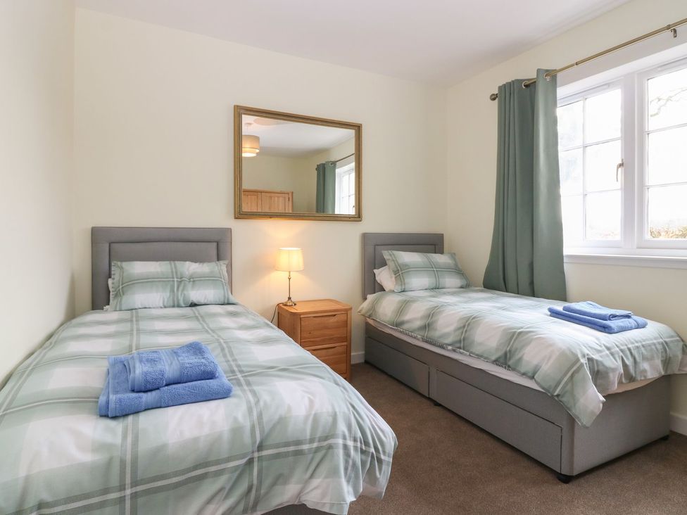 A bedroom with two beds and a mirror at Bankhead Of Lour Bungalow