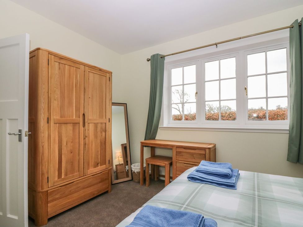 A bedroom with a wardrobe, mirror, and bed at Bankhead Of Lour Bungalow