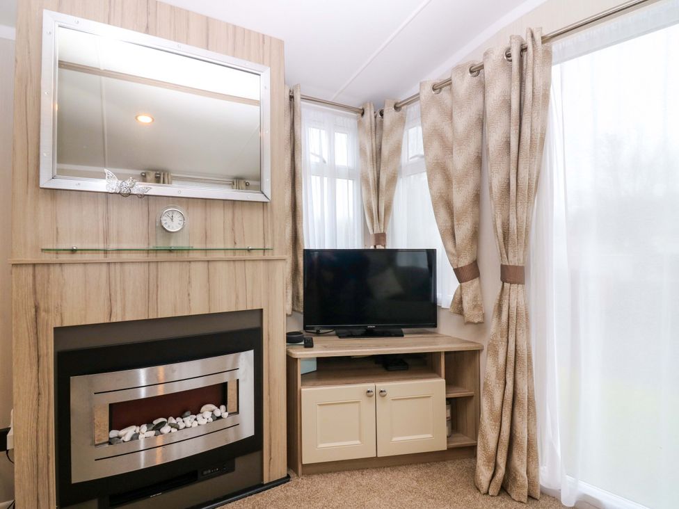 A living room with a television and fireplace at Caravan number 77