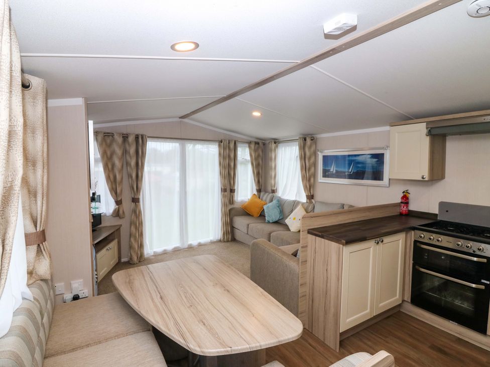 A living room with a sofa and kitchen area at Caravan number 77