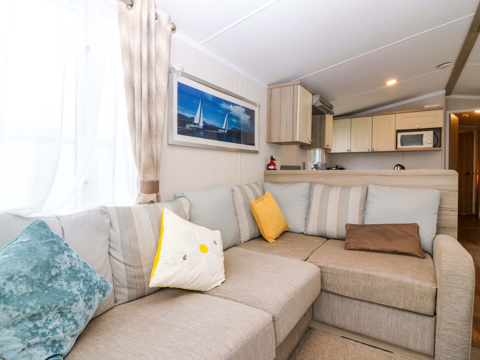 A living room with a sofa and kitchen area at Caravan number 77