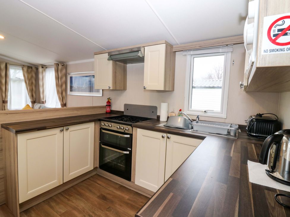 A kitchen with cabinetry, sink, and appliances at Caravan number 77