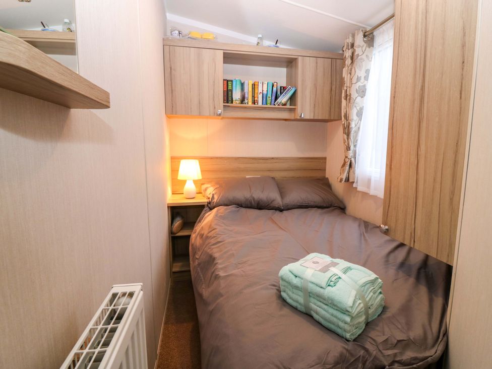 A bedroom with a bed and bookshelf at Caravan number 77 
