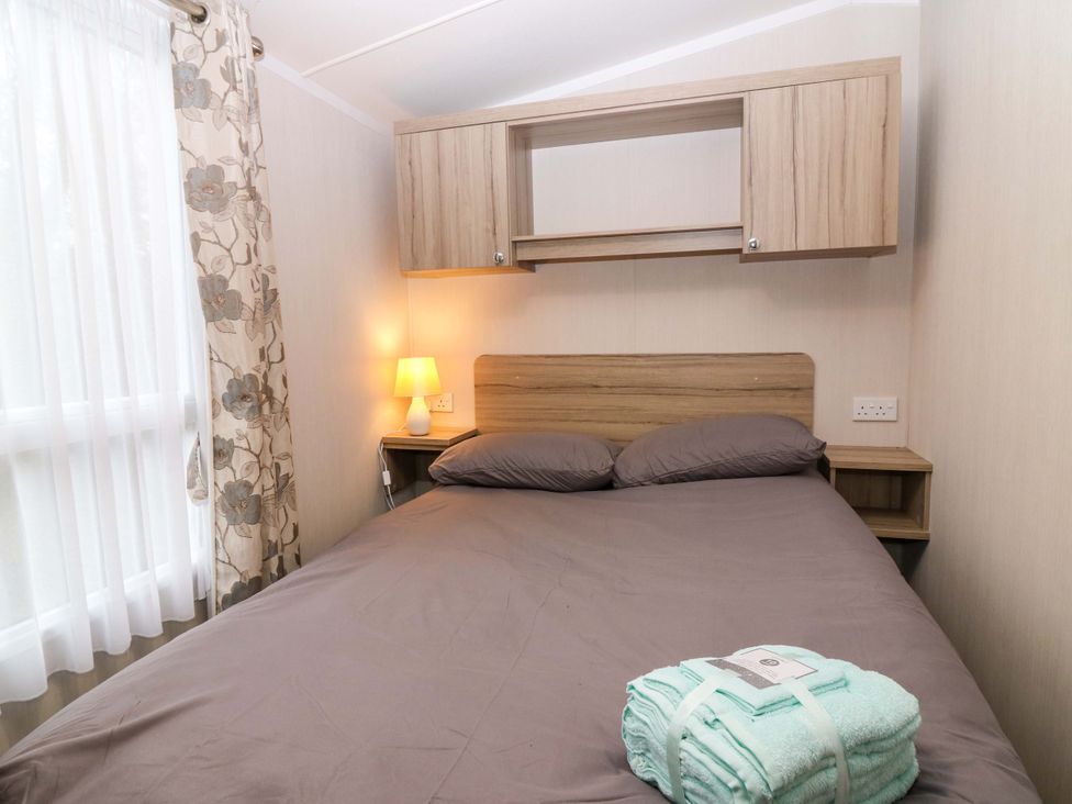 A bedroom with a bed and lamp at Caravan number 77