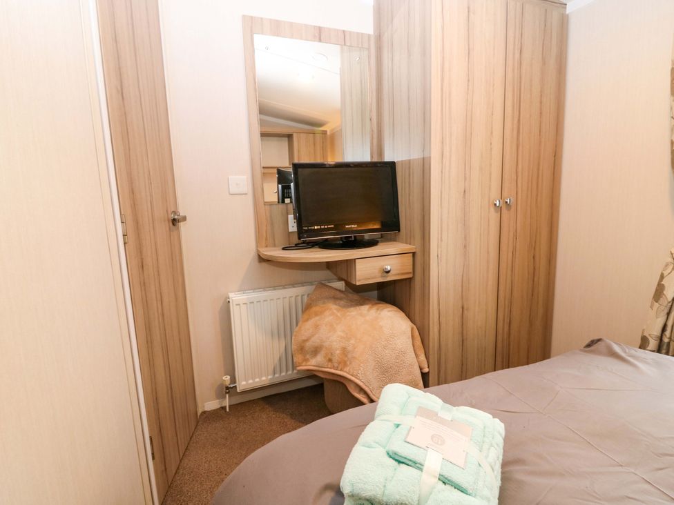A bedroom with a television and mirror at Caravan number 77