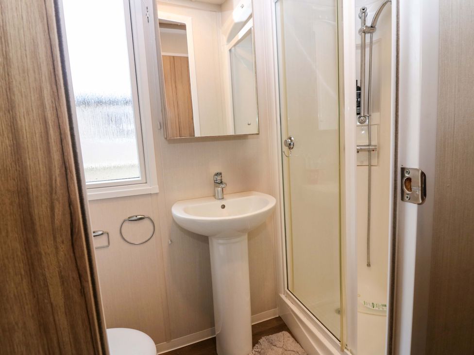 A bathroom with a sink, shower, and toilet at Caravan number 77
