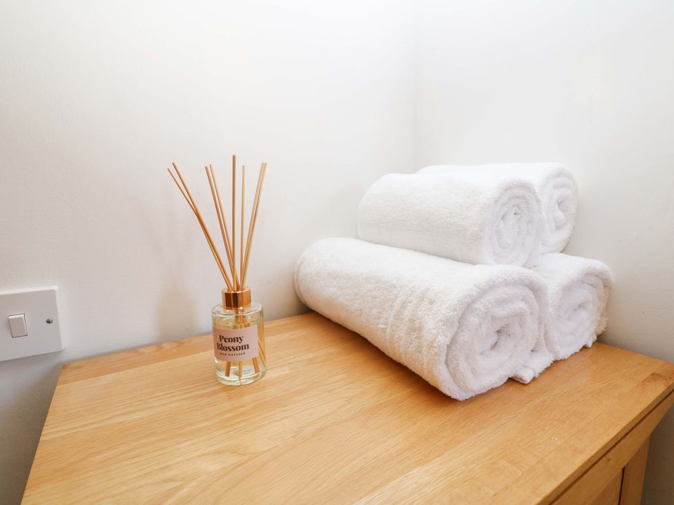 A stacked towels and a diffuser on a table at 53 Orchard Place