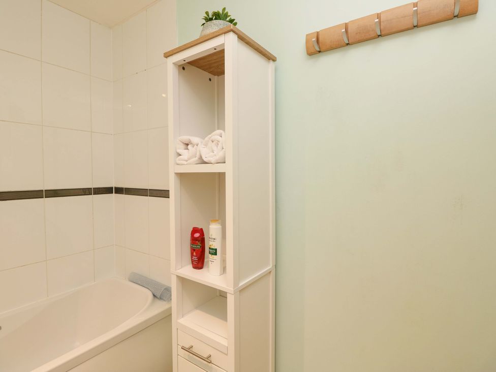 A bathroom featuring a bathtub and a white shelf with towels and toiletries at 53 Orchard Place