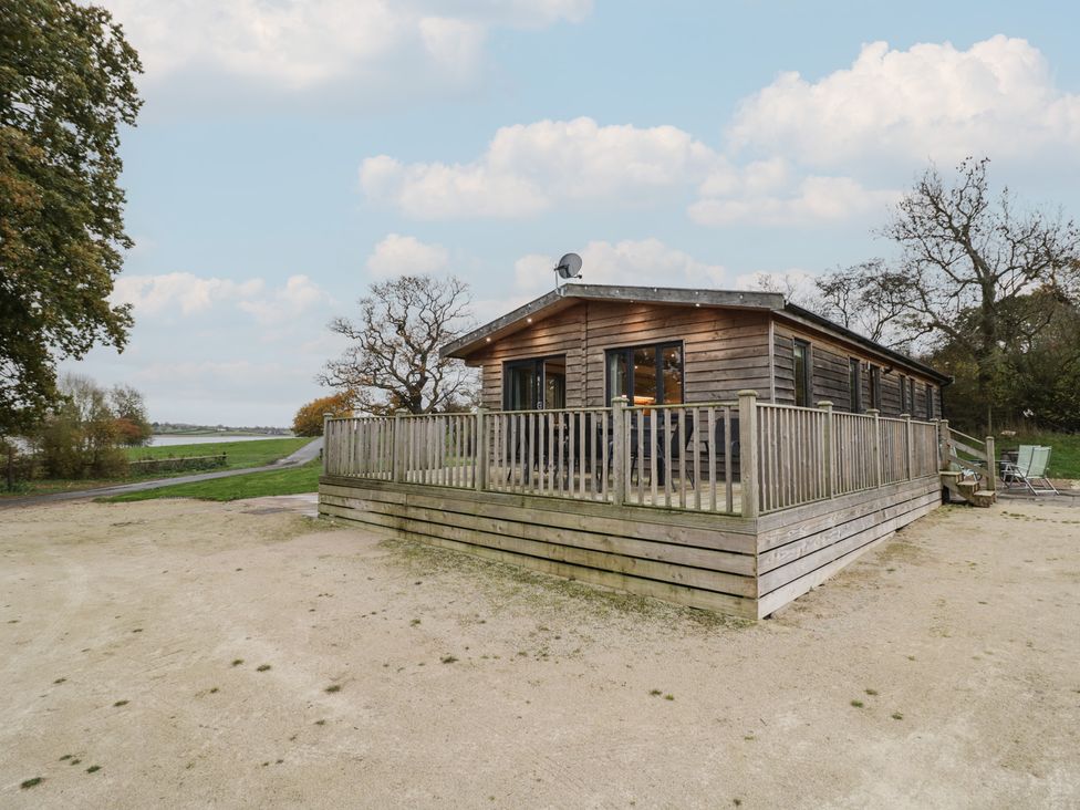 A log cabin with a wooden deck and pathway at Oak Lodge in Admaston near Abbots Bromley