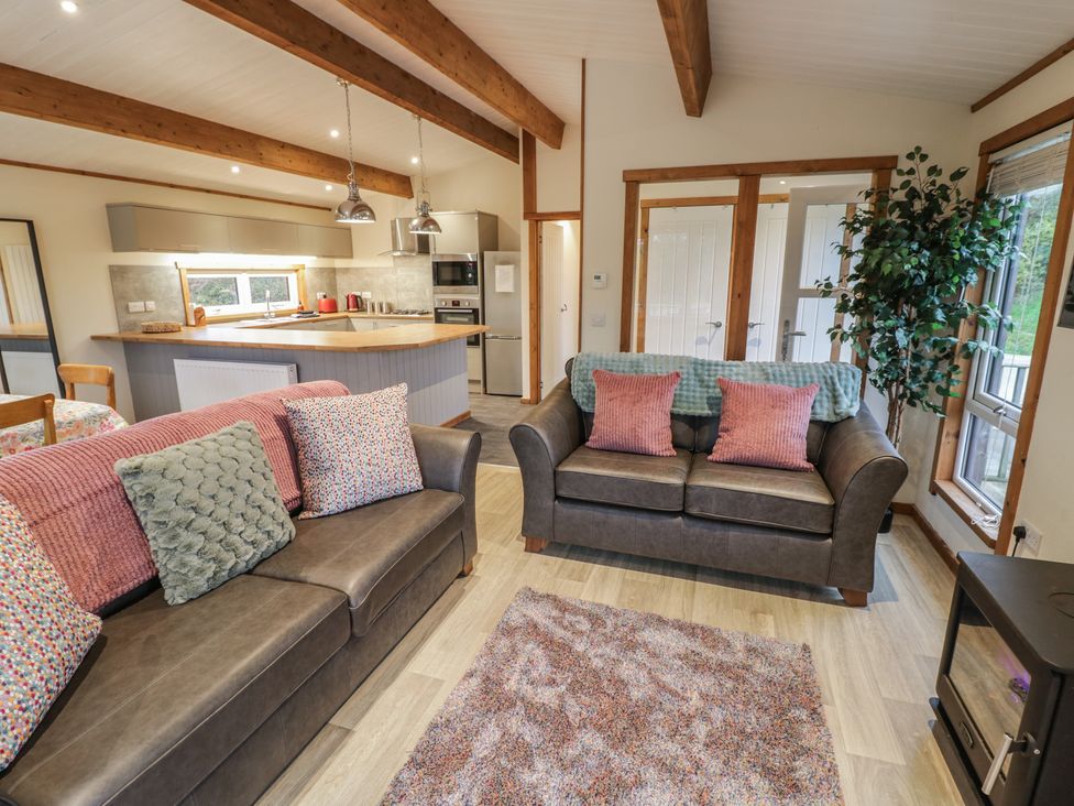 A living room with sofas and kitchen area at Oak Lodge in Admaston near Abbots Bromley
