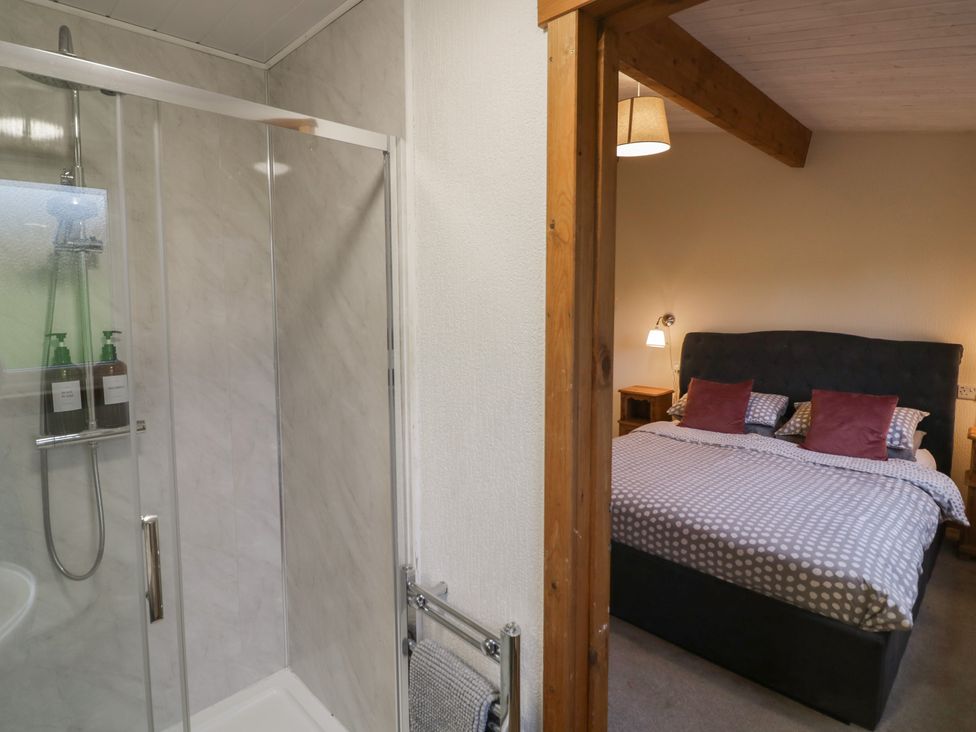A bathroom with a shower and a bedroom featuring a bed at Oak Lodge in Admaston near Abbots Bromley