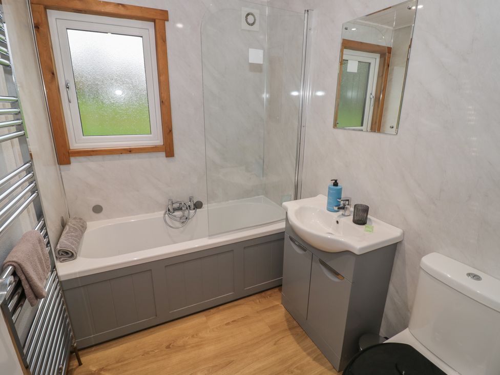 A bathroom with a bathtub and a sink at Oak Lodge in Admaston near Abbots Bromley