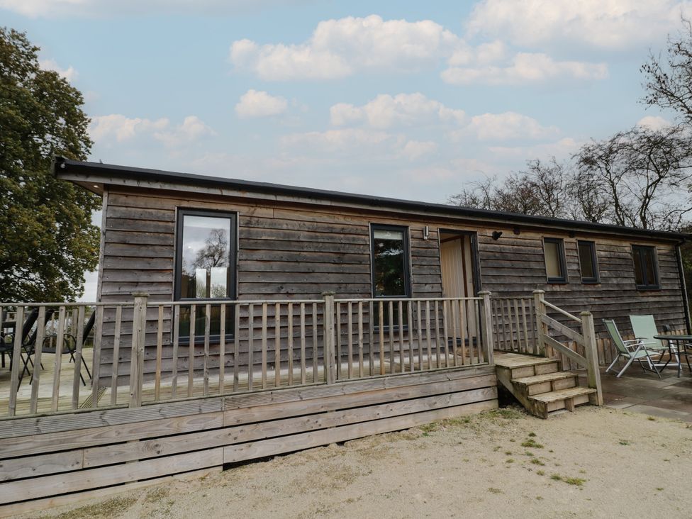 A wooden cabin with steps and outdoor seating at Oak Lodge in Admaston near Abbots Bromley