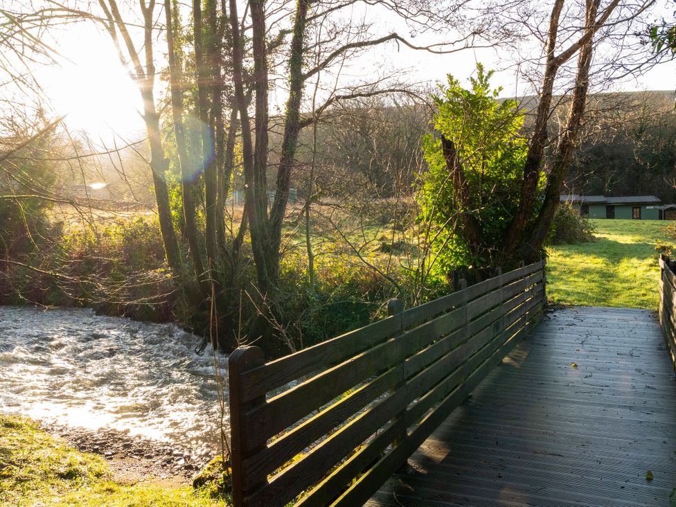 A bridge over a stream with trees and a cabin at 3-bedroom Cabin (1 of 13) Port Talbot