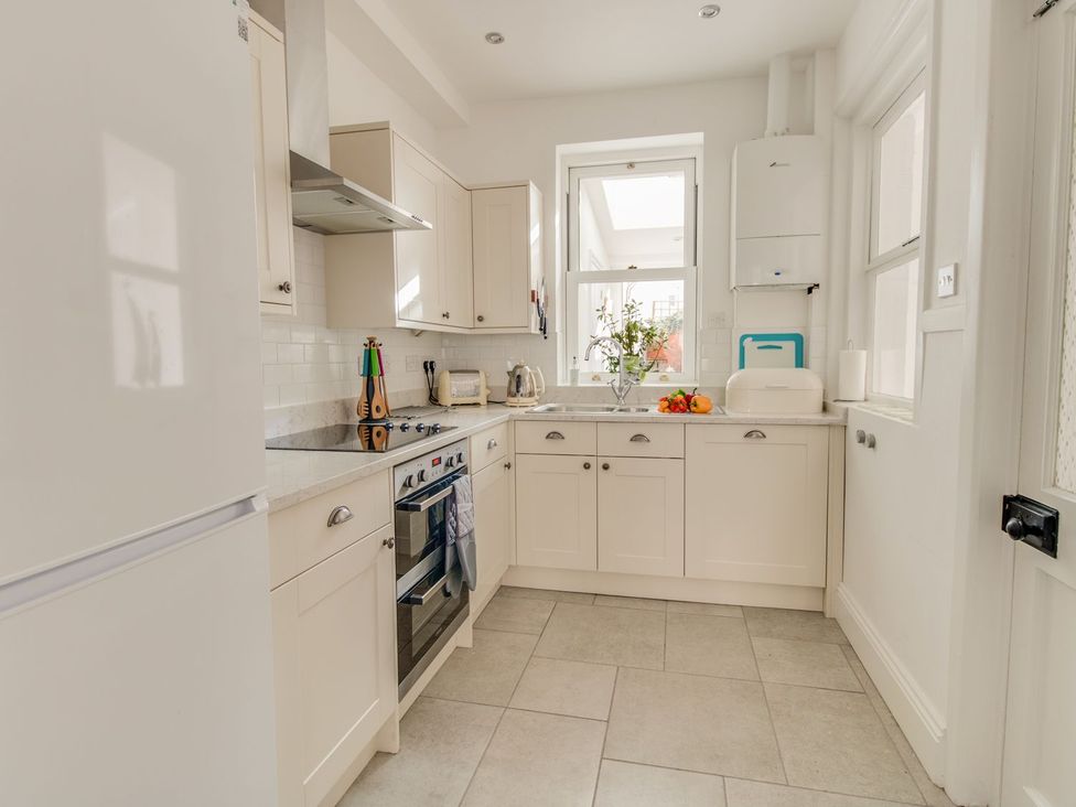 A kitchen with cabinets and appliances at Seahorse Cottage in Weymouth