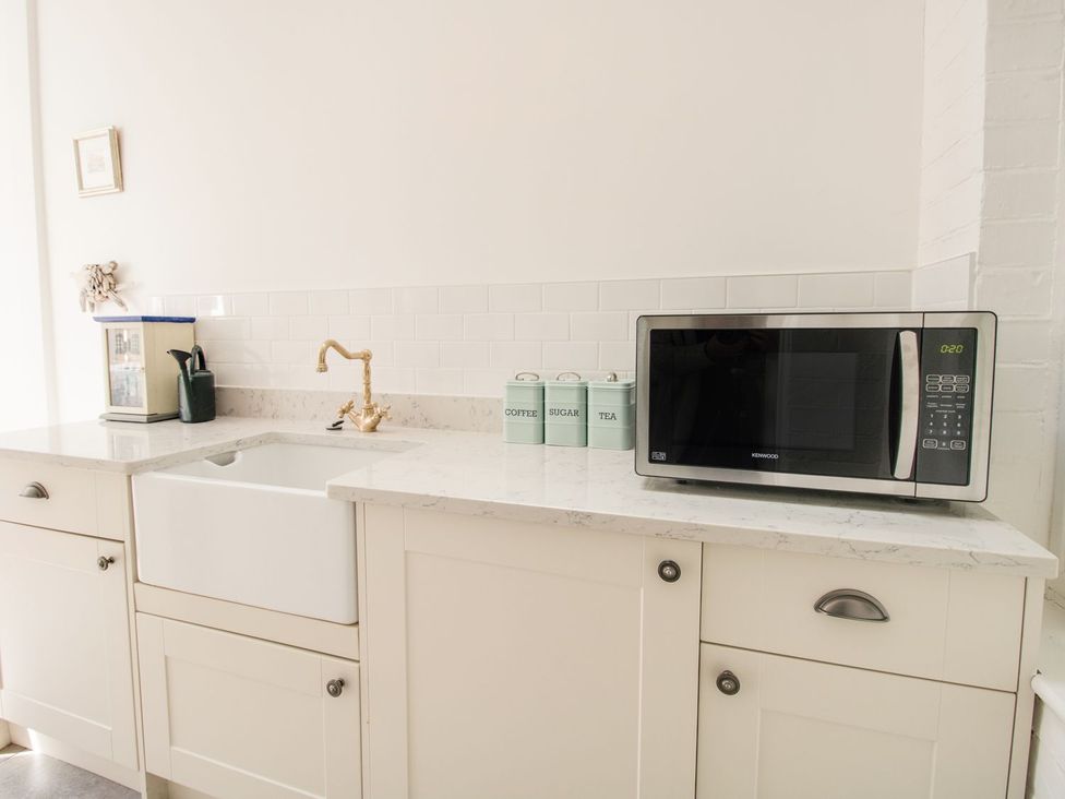 A kitchen with a sink and microwave at Seahorse Cottage in Weymouth