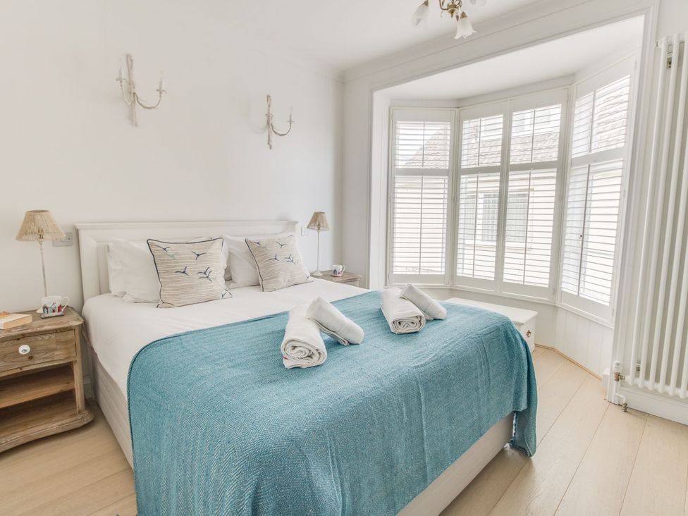 A bedroom with a bed and a bay window at Seahorse Cottage in Weymouth