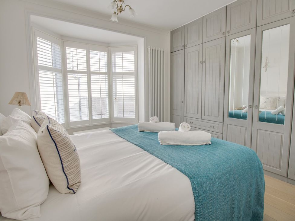 A bedroom with a bed and wardrobe at Seahorse Cottage in Weymouth
