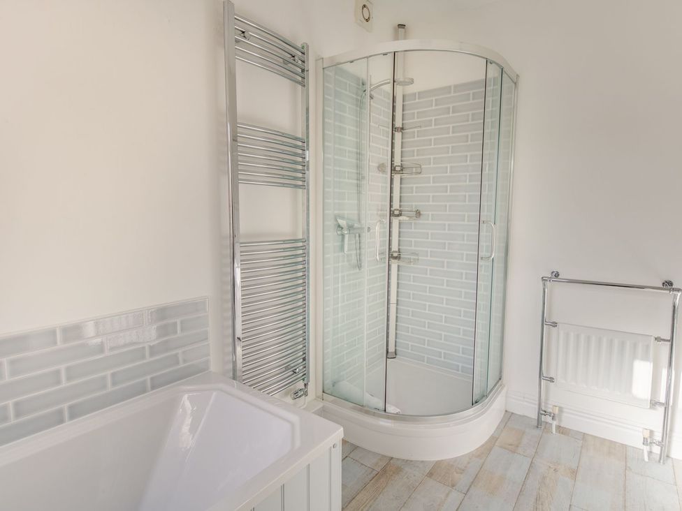 A bathroom with a shower and bathtub at Seahorse Cottage in Weymouth