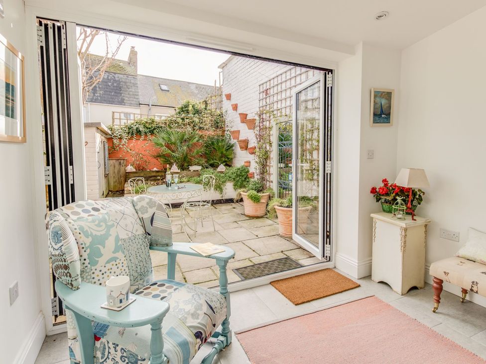 A living room with an armchair and sliding doors leading to a garden at Seahorse Cottage in Weymouth