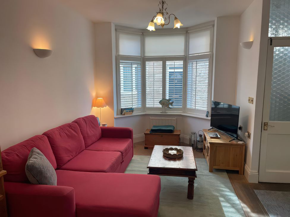 A living room with a pink sofa and wooden coffee table at Seahorse Cottage in Weymouth