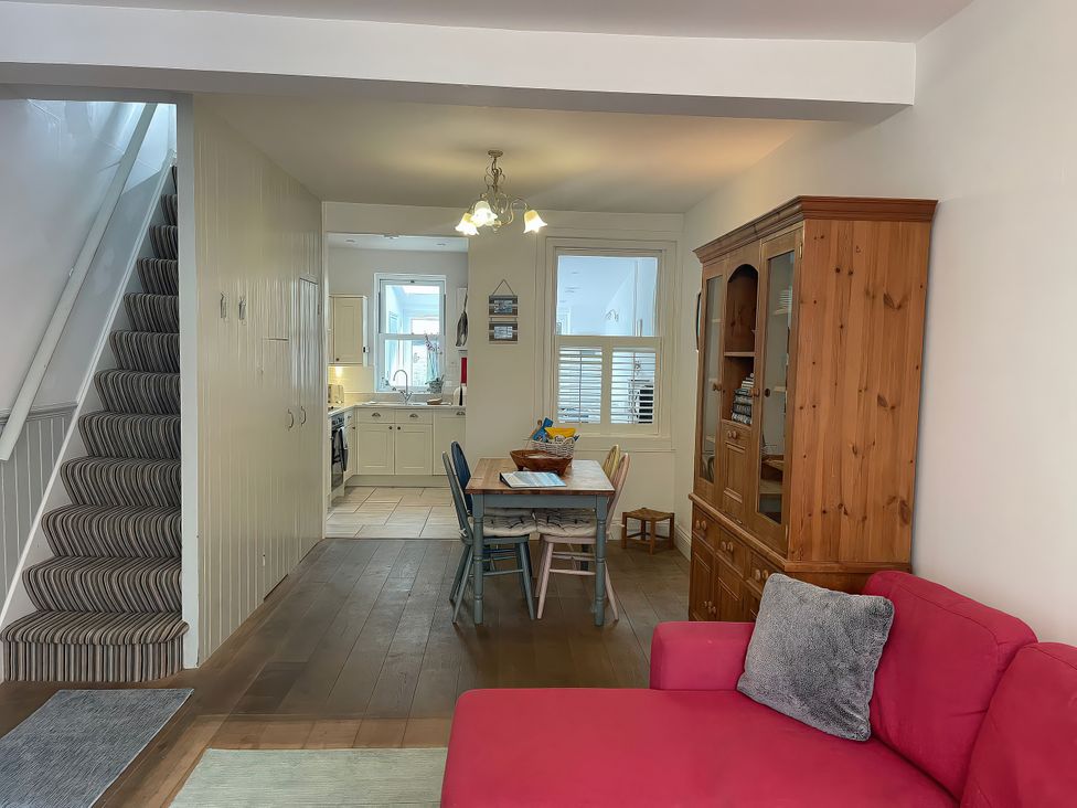 A living room with staircase and dining area at Seahorse Cottage in Weymouth