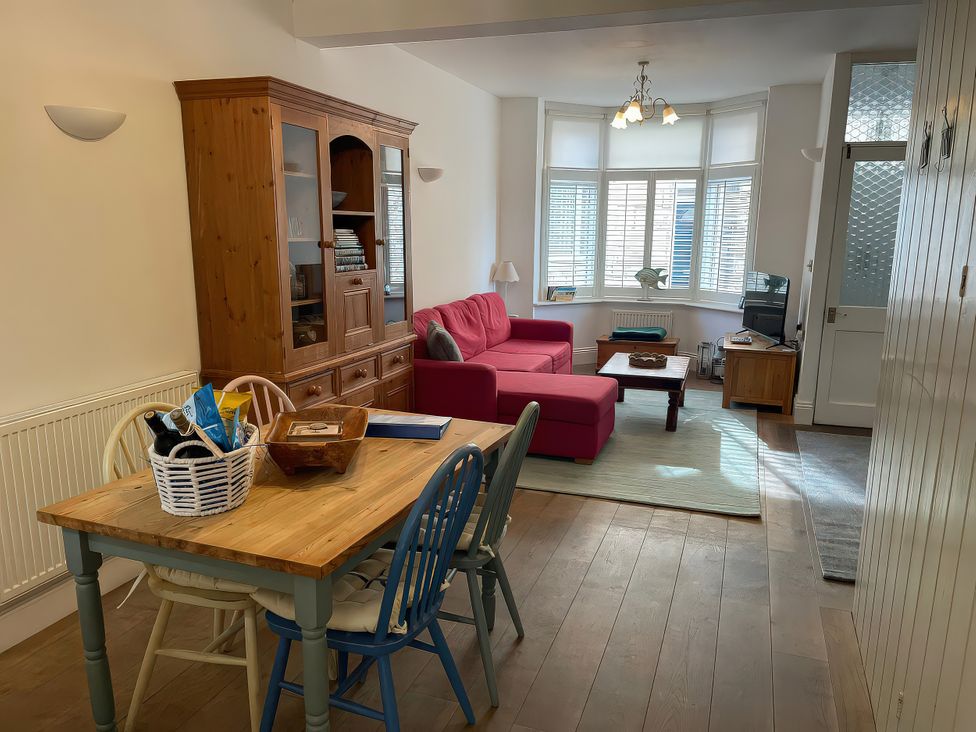 A living room with a sofa and dining area at Seahorse Cottage in Weymouth