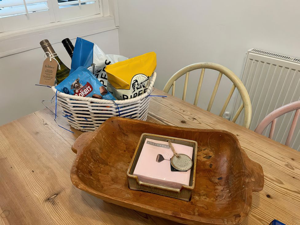 A dining room table with a basket of snacks and drinks at Seahorse Cottage in Weymouth