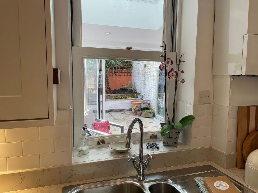 A kitchen with a sink and window showing a garden at Seahorse Cottage in Weymouth