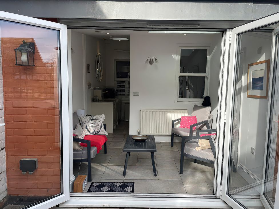 A conservatory with seating and a table at Seahorse Cottage in Weymouth